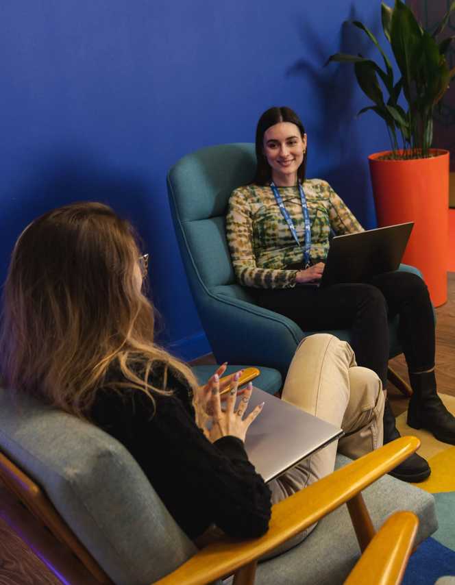 Two women in a break room at the London PlayStation chatting.