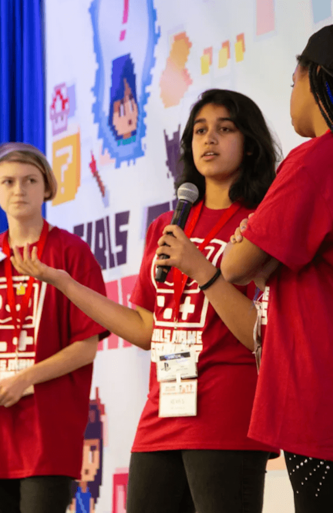 Award ceremony, three girls accepting medals for their GMG accomplishments.